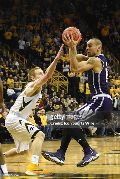 Iowa Hawkeyes guard Mike Gesell tries to block a shot by Northwestern guard Tre Demps during a Big Ten Conference mens basketball game between the...