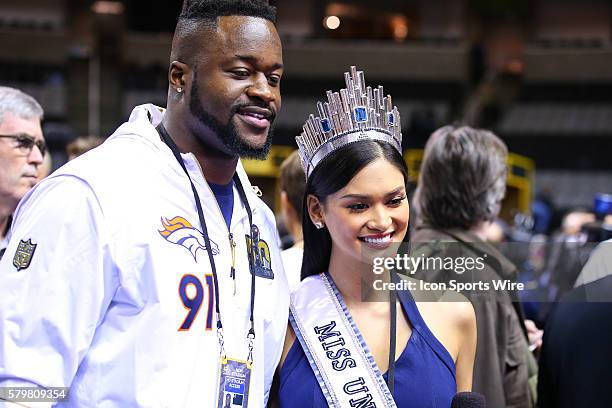 Denver Broncos defensive end Kenny Anunike poses for a photo with Miss Universe on the floor during Super Bowl 50 Opening Night held at the SAP...