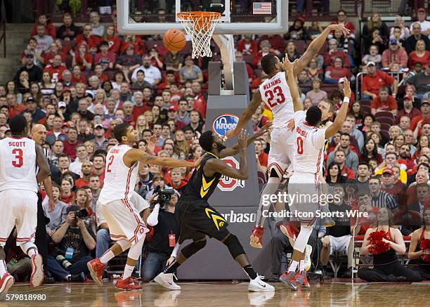 Mike Gesell of the Iowa Hawkeyes passes the ball in-between Amir Williams of the Ohio State Buckeyes and D'Angelo Russell of the Ohio State Buckeyes...