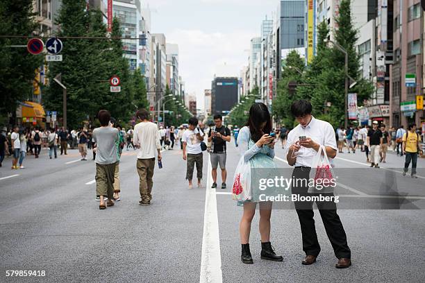 People play Nintendo Co.'s Pokemon Go augmented-reality game, developed by Niantic Inc., on their smartphones on a street in the Akihabara district...