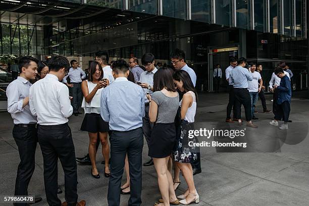 Office workers play Nintendo Co.'s Pokemon Go augmented-reality game, developed by Niantic Inc., on their smartphones at the HSBC Holdings Plc...