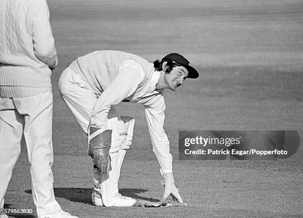 Alan Knott of England picks up one of his wicketkeeping gloves during the Test Trial match between England and The Rest at Worcester, England, 30th...