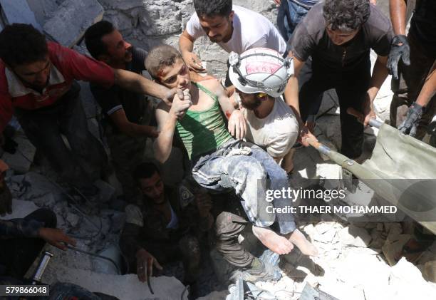 Syrian civil defence volunteers, known as the White Helmets, carry a young boy after they dug him out from under the rubble of buildings destroyed...