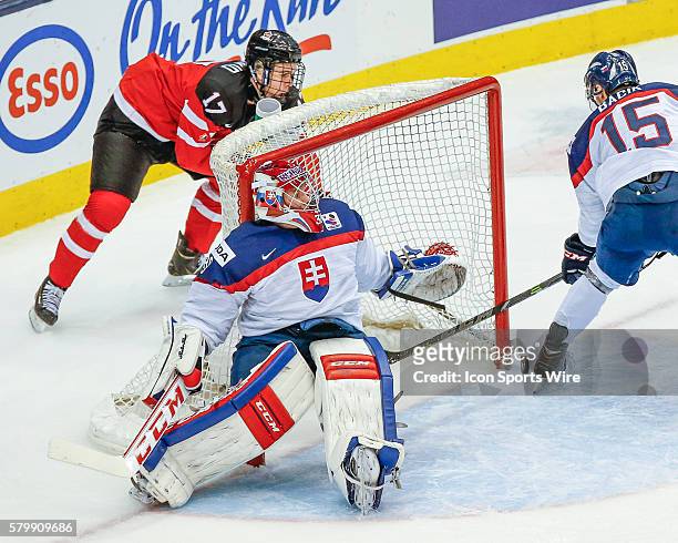 Connor McDavid of Team Canada passes past Denis Godla and Patrik Bacik of Slovakia during Canada's 5-1 victory over Slovakia at the IIHF World Junior...