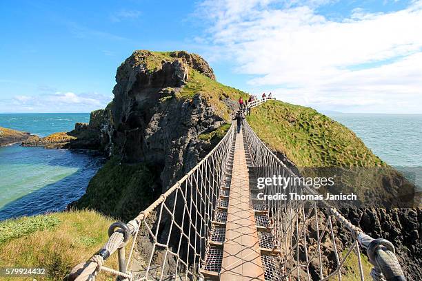 standing on carrick-a-rede rope bridge, a famous rope bridge near ballintoy in county antrim, northern ireland, uk - northern ireland rope bridge stock-fotos und bilder