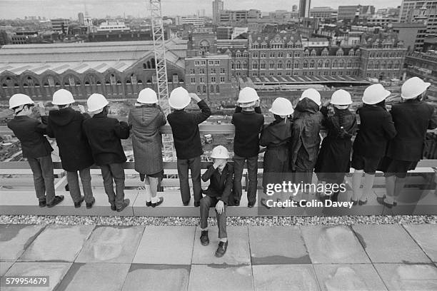 Schoolchildren in hard hats surveying the construction site around Liverpool Street Station in London, 1986.