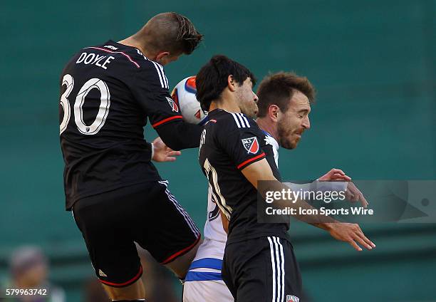 Miguel Aguilar and Conor Doyle of D.C United go up for a header against Eric Alexander of Montreal Impact during a MLS soccer match at RFK Stadium,...