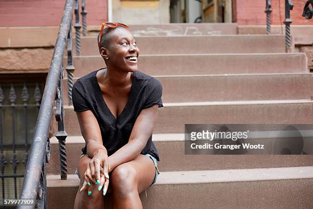 black woman sitting on urban front stoop - portico sopraelevato foto e immagini stock