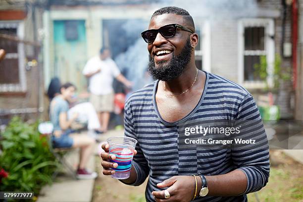 african american man drinking at backyard barbecue - cosmopolitan drink stock pictures, royalty-free photos & images
