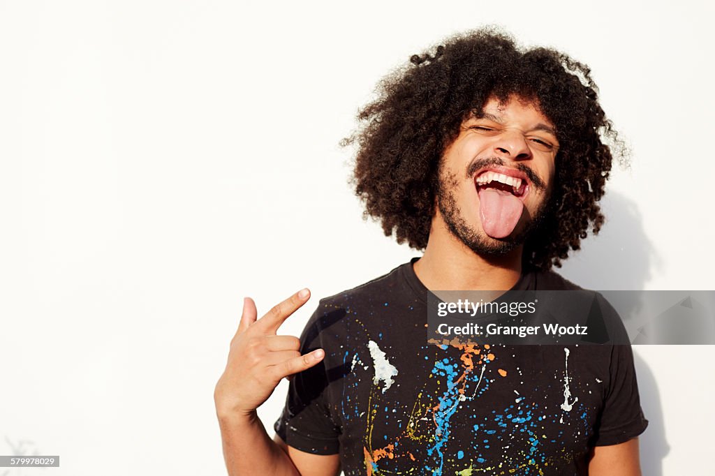 Mixed race man making a face and rock-on hand gesture