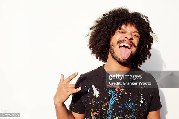 mixed race man making a face and rock-on hand gesture - darstellender künstler stock-fotos und bilder