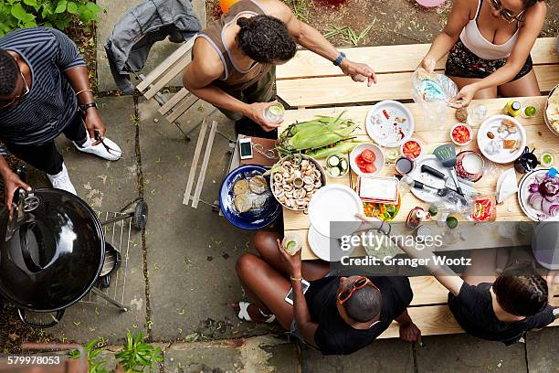 high angle view of friends eating at backyard barbecue - preparación de alimentos fotografías e imágenes de stock