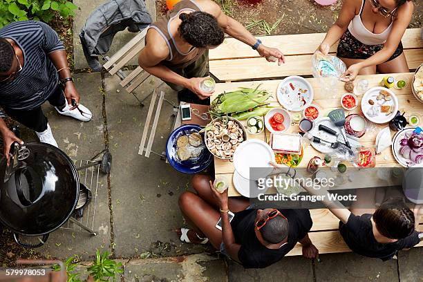high angle view of friends eating at backyard barbecue - black man high 5 stockfoto's en -beelden