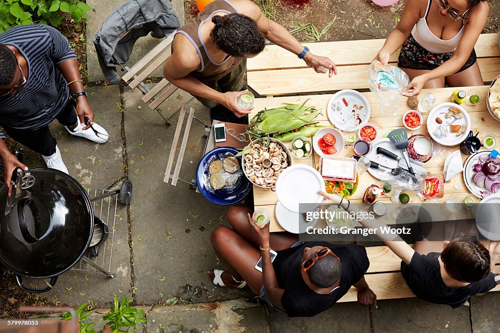 High Angle View Of Friends Eating At Backyard Barbecue High-Res