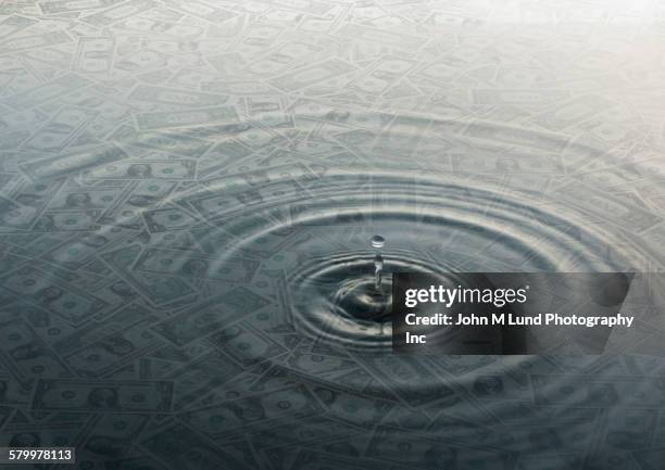 ripple of water over dollar bills - cashflow stock pictures, royalty-free photos & images