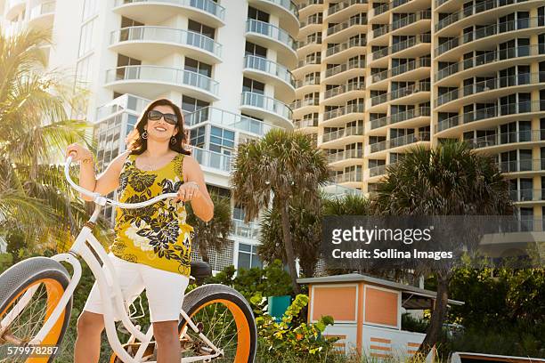 hispanic woman pushing bicycle in city - miami fahrrad stock-fotos und bilder
