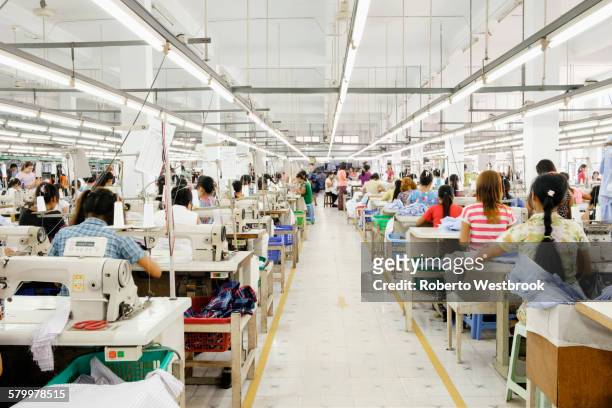 asian worker sewing clothing in garment factory - klädesplagg bildbanksfoton och bilder