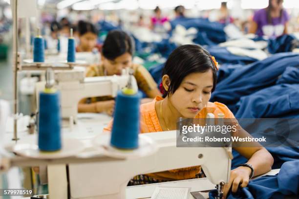asian worker sewing clothing in garment factory - fábrica textil fotografías e imágenes de stock