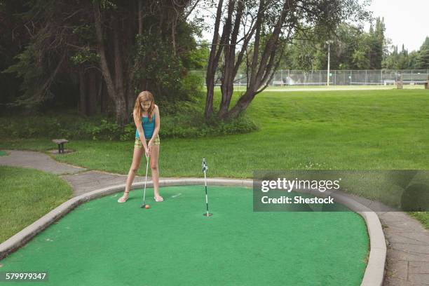 caucasian girl playing miniature golf - golf girls stock-fotos und bilder