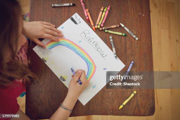 caucasian girl drawing rainbow with crayons on table - crayola stock pictures, royalty-free photos & images