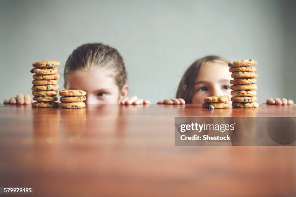 caucasian girls staring at cookies on table - children looking graph stock pictures, royalty-free photos & images