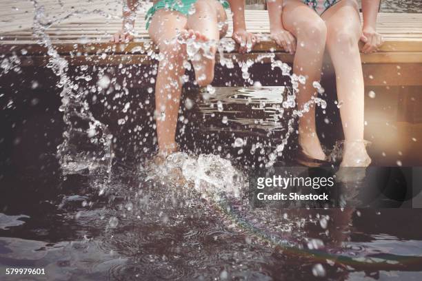 caucasian girls splashing in lake from wooden dock - tween heels stock pictures, royalty-free photos & images