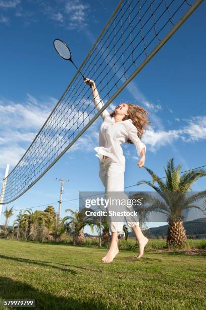 woman playing badminton in park - badminton stock-fotos und bilder