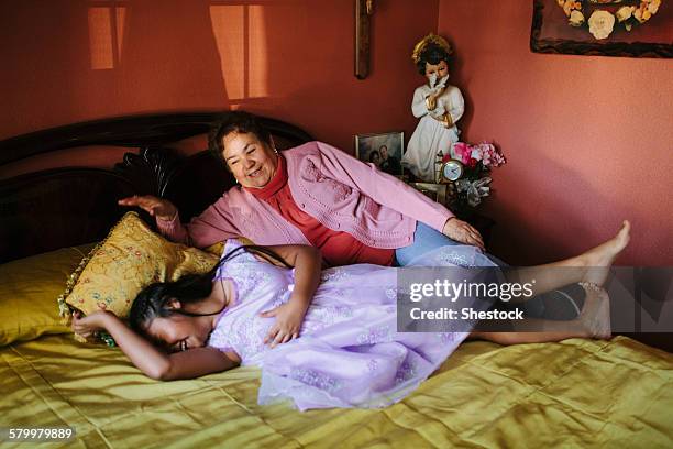 hispanic grandmother and granddaughter laying on bed - chubby granny stock pictures, royalty-free photos & images