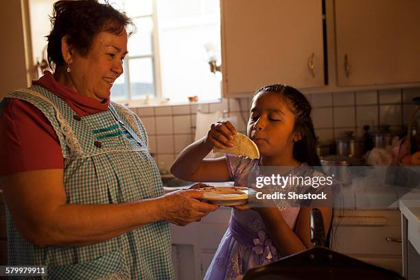 hispanic woman cooking for granddaughter in kitchen - granny stockfoto's en -beelden