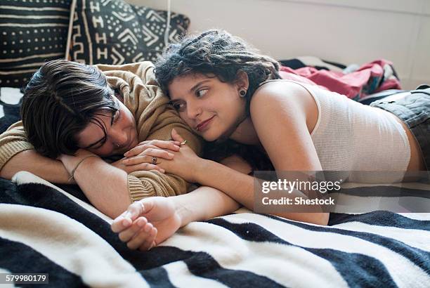 smiling couple laying on bed - lesbian bed stock pictures, royalty-free photos & images