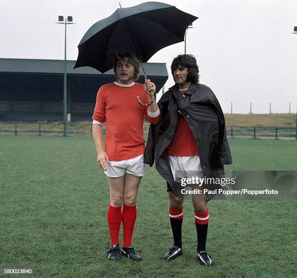Sheltering from the weather, Manchester United footballer George Best with actor Hywel Bennett during the filming of 'Percy' at the Cliff training...