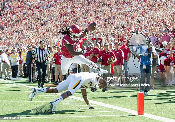 Arkansas Razorbacks running back Alex Collins leaps over Toledo Rockets defensive back DeJuan Rogers for a touchdown during the Toledo versus...