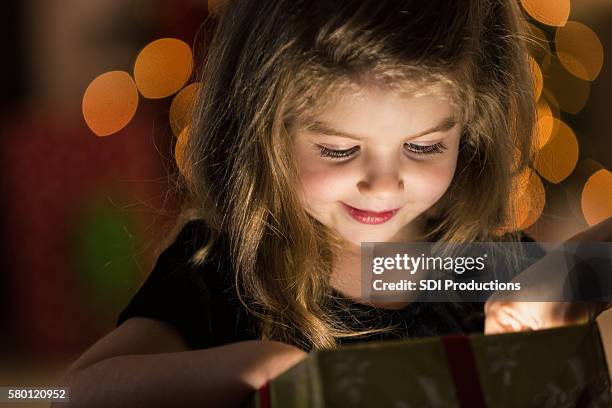 curious girl peeks inside a christmas present - christmas present bildbanksfoton och bilder