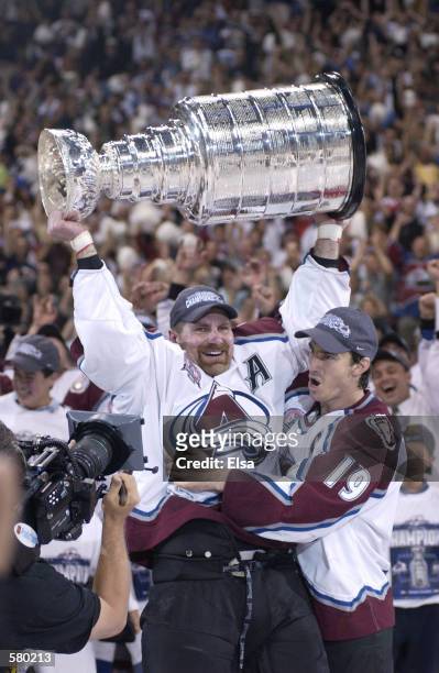 Ray Bourque of the Colorado Avalanche lifts the cup as teammate Joe Sakic hugs after the Colorado Avalanche defeated the New Jersey Devils 3-1 in...