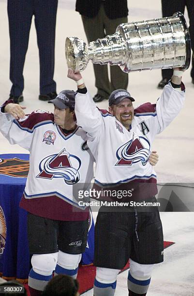 Joe Sakic and Ray Borque of the Colorado Avalanche hold up the Stanley Cup after defeating the New Jersey Devils in game seven of the NHL Stanley Cup...