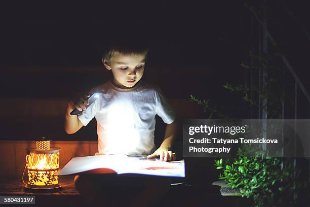 sweet boy reading a book on the stairs - lantern stock pictures, royalty-free photos & images