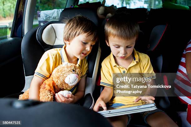 two cute boys, playing on tablet in the car - back seat stock pictures, royalty-free photos & images