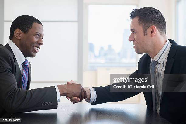 businessmen shaking hands in office meeting - arbitration agreement stock pictures, royalty-free photos & images