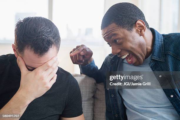 close up of man teasing friend on sofa - teasing stock pictures, royalty-free photos & images