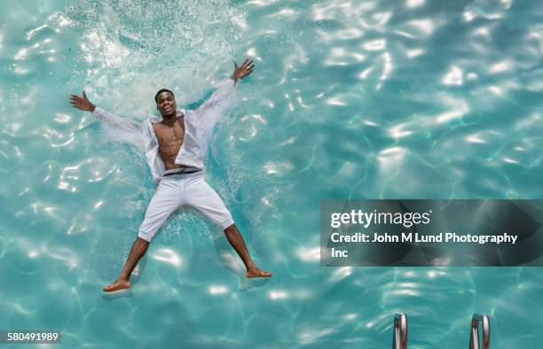 african american man floating in swimming pool - floating on water stock pictures, royalty-free photos & images