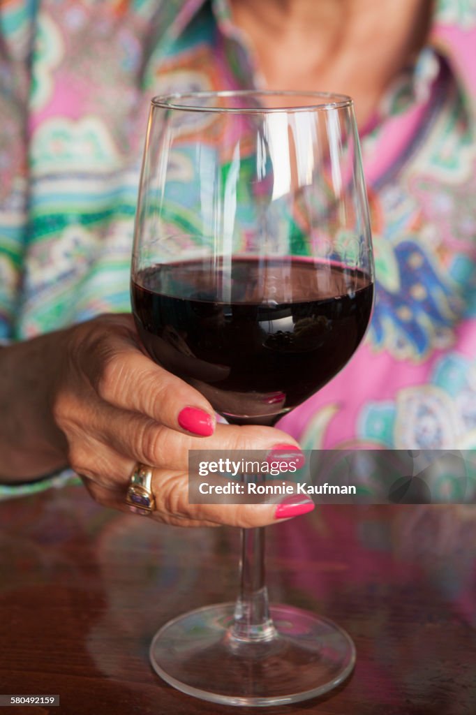 Older Hispanic woman drinking glass of wine in restaurant
