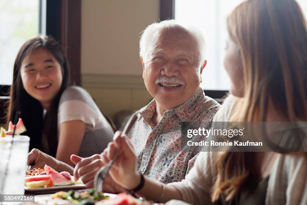 grandfather and granddaughters talking in restaurant booth - asians eating stock pictures, royalty-free photos & images