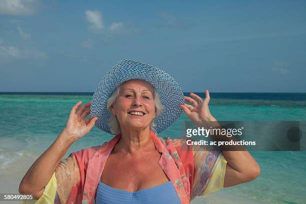 older caucasian woman smiling on beach - vilamendhoo stock-fotos und bilder