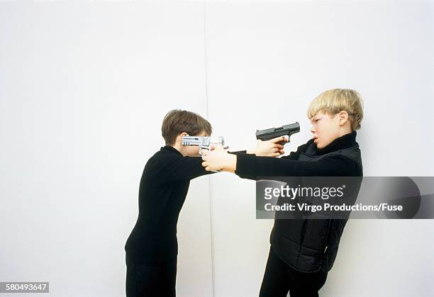 two boys threatening themselves with guns - children role playing crime stock-fotos und bilder