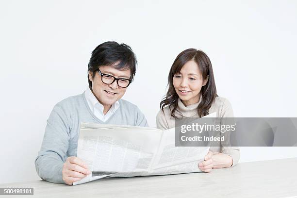 couple reading newspaper together - côte à côte photos et images de collection
