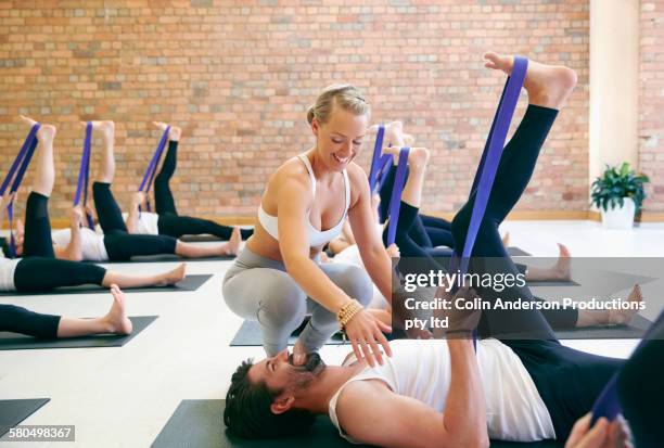 instructor assisting student using resistance band in yoga class - connected mindfulness work stock pictures, royalty-free photos & images