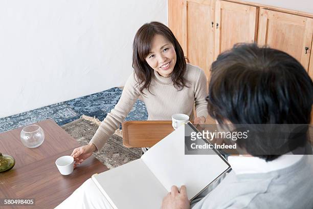 mature woman serving coffee to senior man  - coffee table reading mug stock pictures, royalty-free photos & images