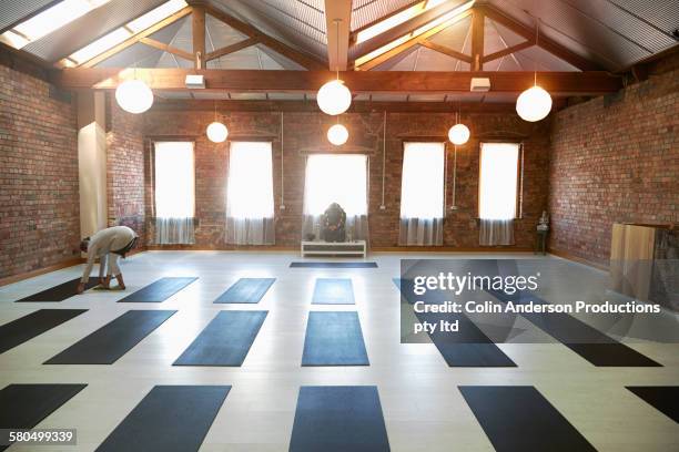 caucasian woman arranging mats in yoga studio - yoga studio stock pictures, royalty-free photos & images