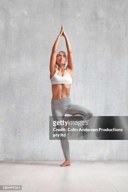 caucasian woman practicing yoga in studio - tree position stock pictures, royalty-free photos & images