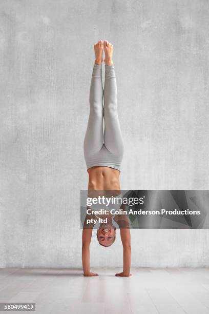 caucasian woman practicing yoga in studio - handstand stock pictures, royalty-free photos & images